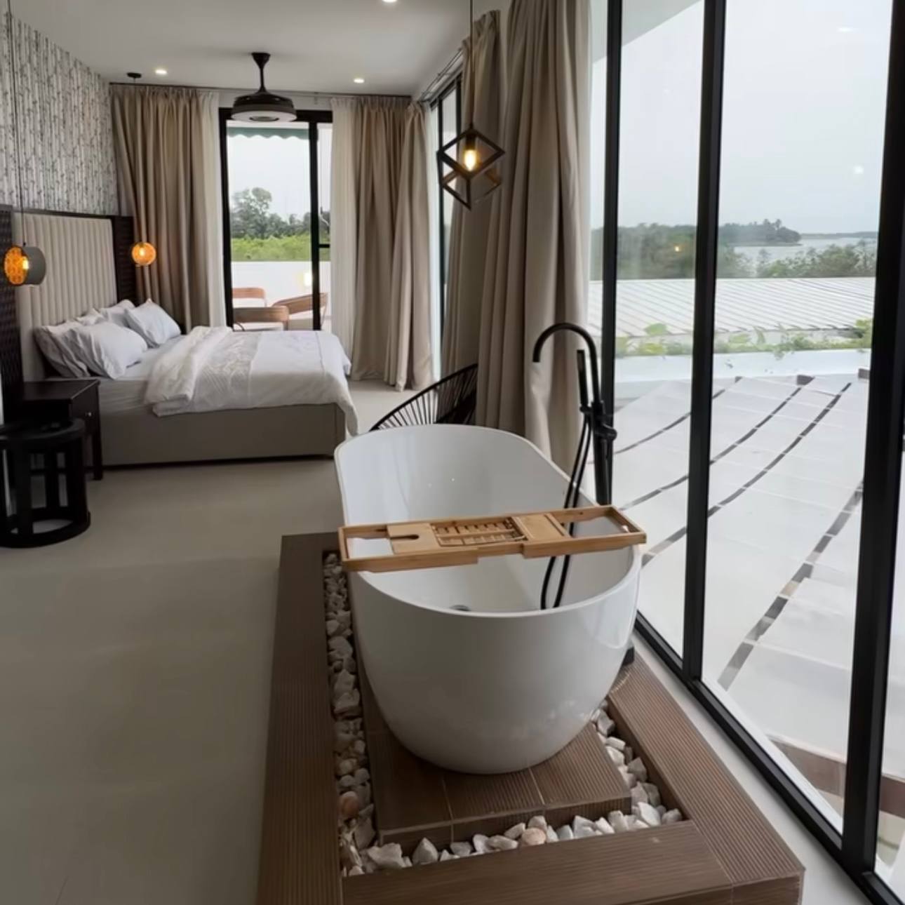Suite with freestanding bath, bed and tall windows over the water