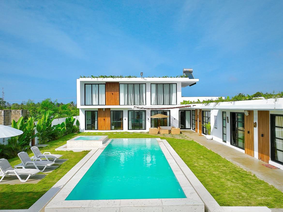 The villa facade in morning light behind the turquoise pool