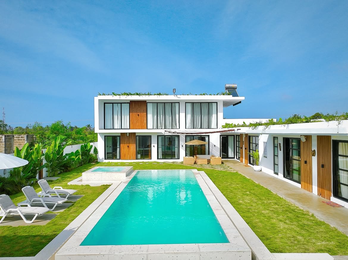 THE LOVLACE villa exterior with its long pool and lawn under a clear sky